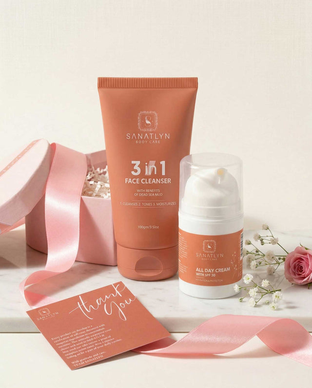 Sanatlyn skincare products including a 3-in-1 face cleanser and all-day cream on a white surface with pink ribbon and flowers.
