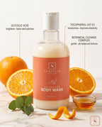Sanatlyn Hydrating & Brightening Body Wash bottle with oranges and eucalyptus leaves on a marble surface