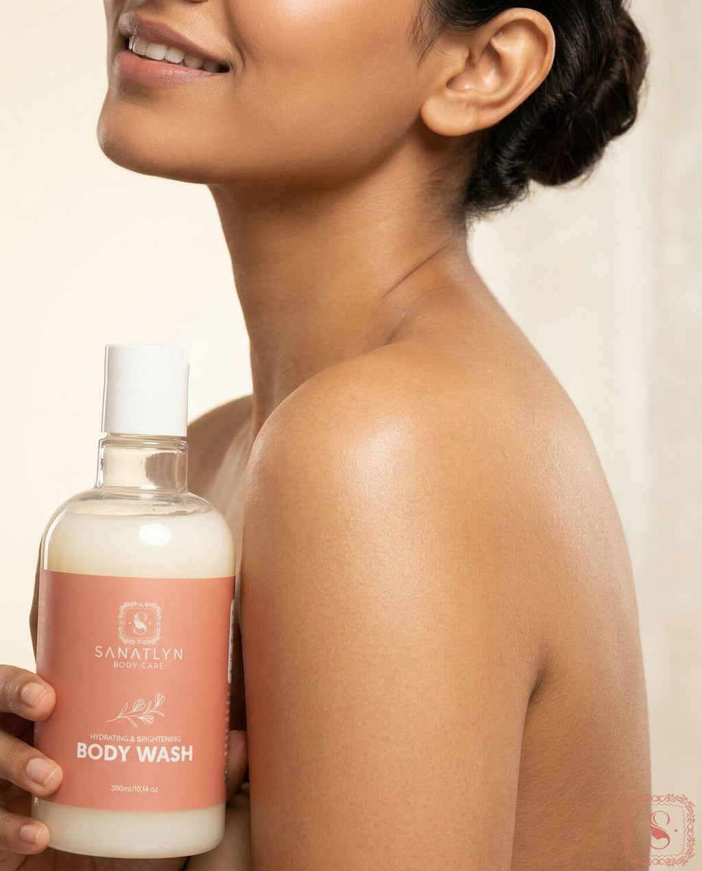 Person holding a bottle of Sanatlyn Hydrating & Brightening Body Wash against a neutral background
