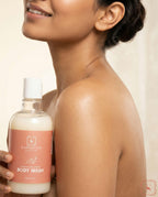 Person holding a bottle of Sanatlyn Hydrating & Brightening Body Wash against a neutral background